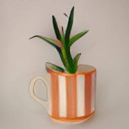 a blue and white striped cup orange illustration handle left 
                            used as a plant pot in studio