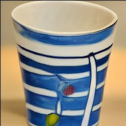 a photo of a blue and white striped cup with a fruit painted on it