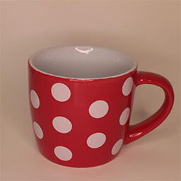 A big cylindric cup with a handle facing right 
                            A bright red cup with big white dots 
                            An empty cup in studio