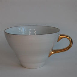 A wide cup with a handle facing right 
                            A old white cup with a golden handle and golden rim 
                            An empty cup in studio