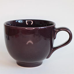 A wide rounded cup with a handle facing right 
                            A dark brown cup 
                            An empty cup in studio