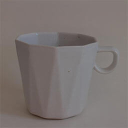 A cone shaped cup with a handle facing right 
                            A white cup in origami style 
                            An empty cup in studio