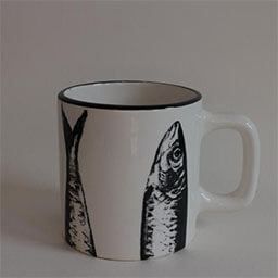 A cylindric cup with an angular handle facing right 
                            A white cup printed with fish illustrations 
                            An empty cup in studio
