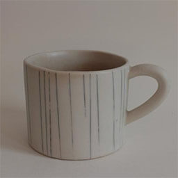 A cylindric cup with a handle facing right 
                            A white cup painted with thin vertical lines 
                            An empty cup in studio