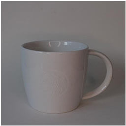 A slightly rounded cup with a big handle facing right 
                            A white cup printed with an engraved Starbucks company logo 
                            An empty cup in studio