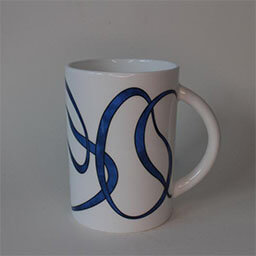 A high cylindric cup with a handle facing right 
                            A white cup printed with a blue line pattern 
                            An empty cup in studio