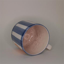 a cylindric cup lying on its side facing front a blue and white striped cup painted with an orange illustration an empty cup in studio