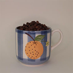 a cylindric cup with a handle facing right a blue and white striped cup painted with an orange illustration 
                            a cup filled with coffee beans in studio