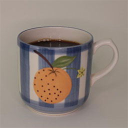 a cylindric cup with a handle facing right a blue and white striped cup painted with an orange illustration 
                            a cup filled with coffee in studio